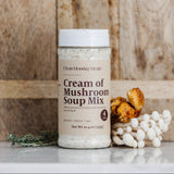 Cream of Mushroom Soup Mix container with dried mushrooms and herbs on a wooden background
