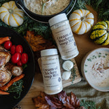 Cream of Chicken Soup Mix bottles on a wooden board with pumpkins and vegetables.