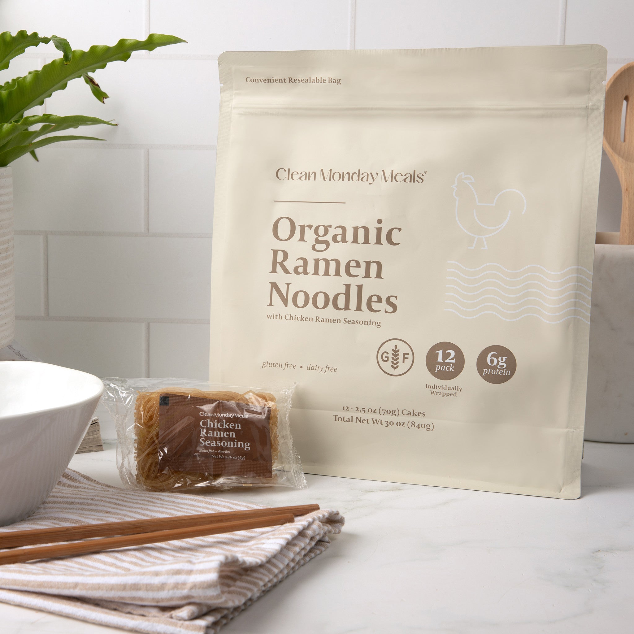 Clean Monday Meals Organic Ramen Noodles package with noodles and seasoning on a kitchen counter.