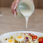 Pouring a mason jar of Clean Monday Meals Ranch Seasoning on a salad.