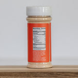 Jar of peanut butter with a red label on a wooden surface and white background