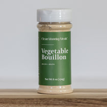 Container of Clean Monday Meats Vegetable Bouillon on a wooden surface with a white background