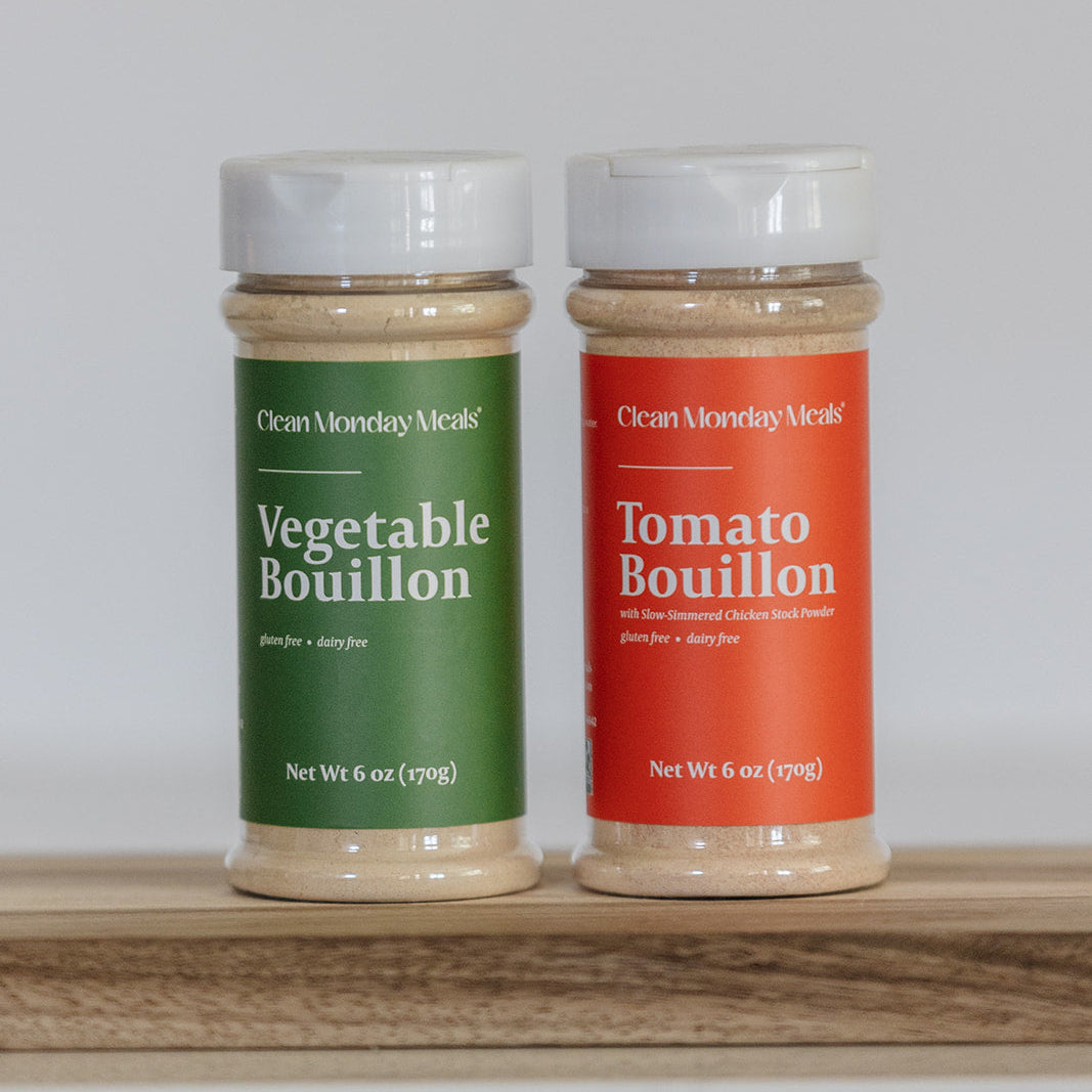 Two bouillon containers, one green and one red, on a wooden surface with a white background.