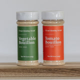 Two bouillon containers, one green and one red, on a wooden surface with a white background.