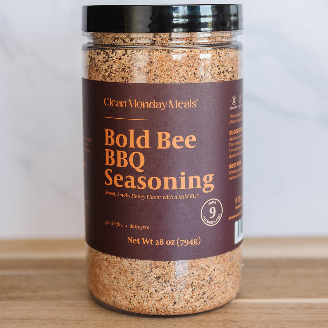 Jar of Bold Bee BBQ Seasoning on a wooden surface with a white background