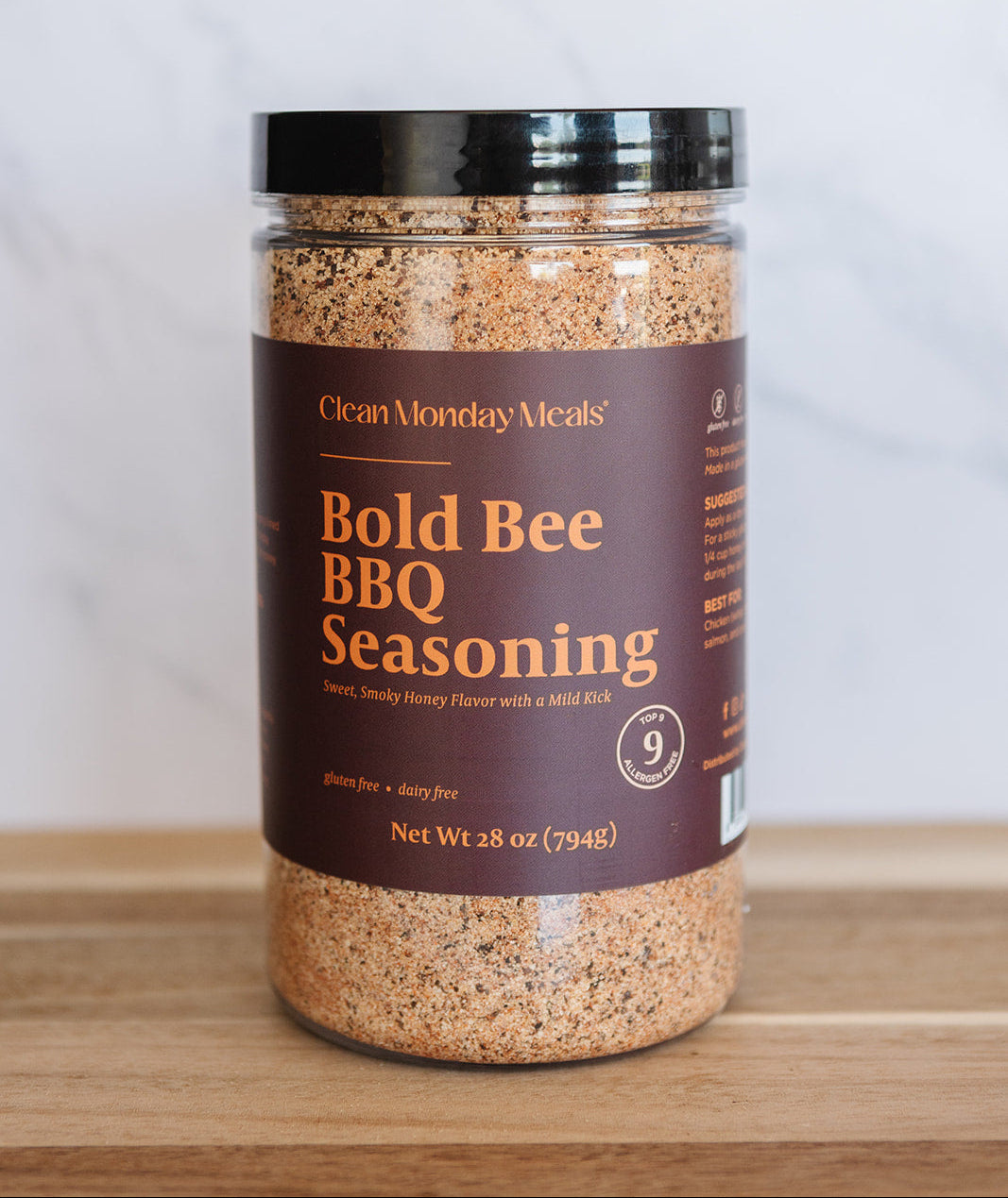 Jar of Bold Bee BBQ Seasoning on a wooden surface with a white background