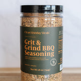 Jar of Grit & Grind BBQ Seasoning on a wooden surface with a white background