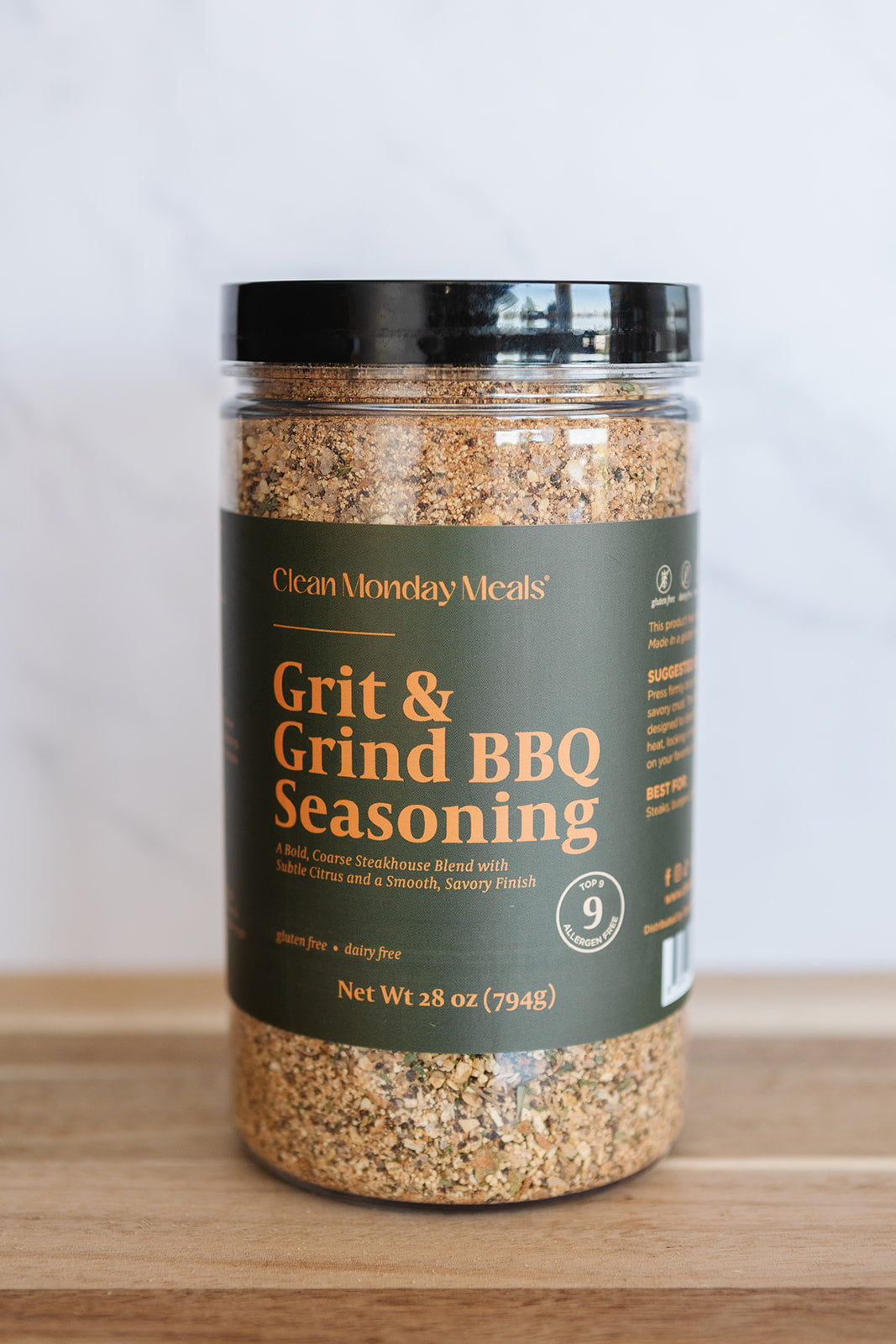 Jar of Grit & Grind BBQ Seasoning on a wooden surface with a white background