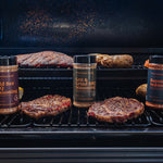 Grill with burgers and seasoning bottles on a barbecue