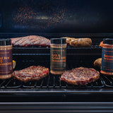 Grill with burgers and seasoning bottles on a barbecue