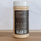 A jar of Diamond's Gourmet Classic Beef Dip, showing the back label, placed on a wooden surface against a light marble background.