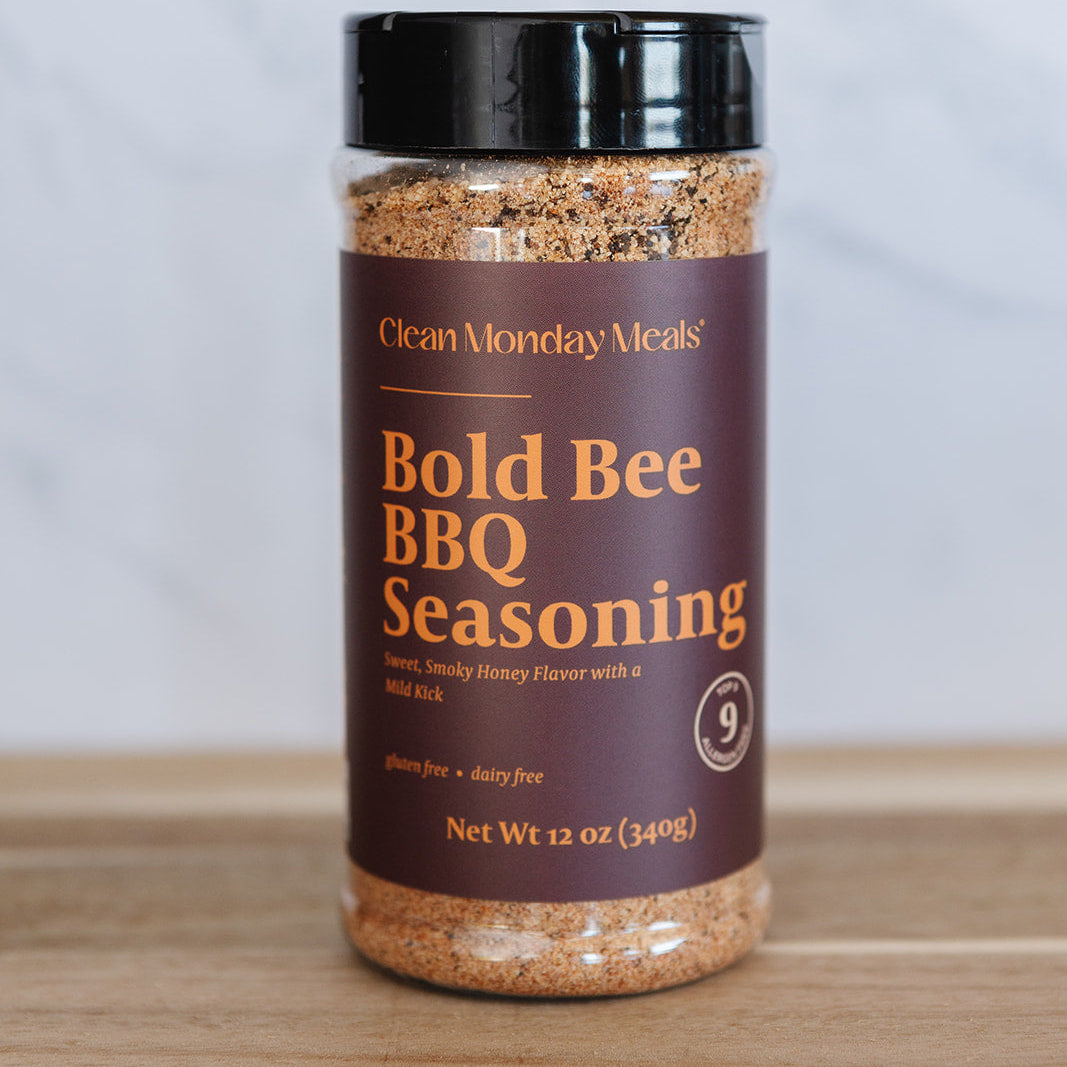 Bottle of Bold Bee BBQ Seasoning on a wooden surface with a white background