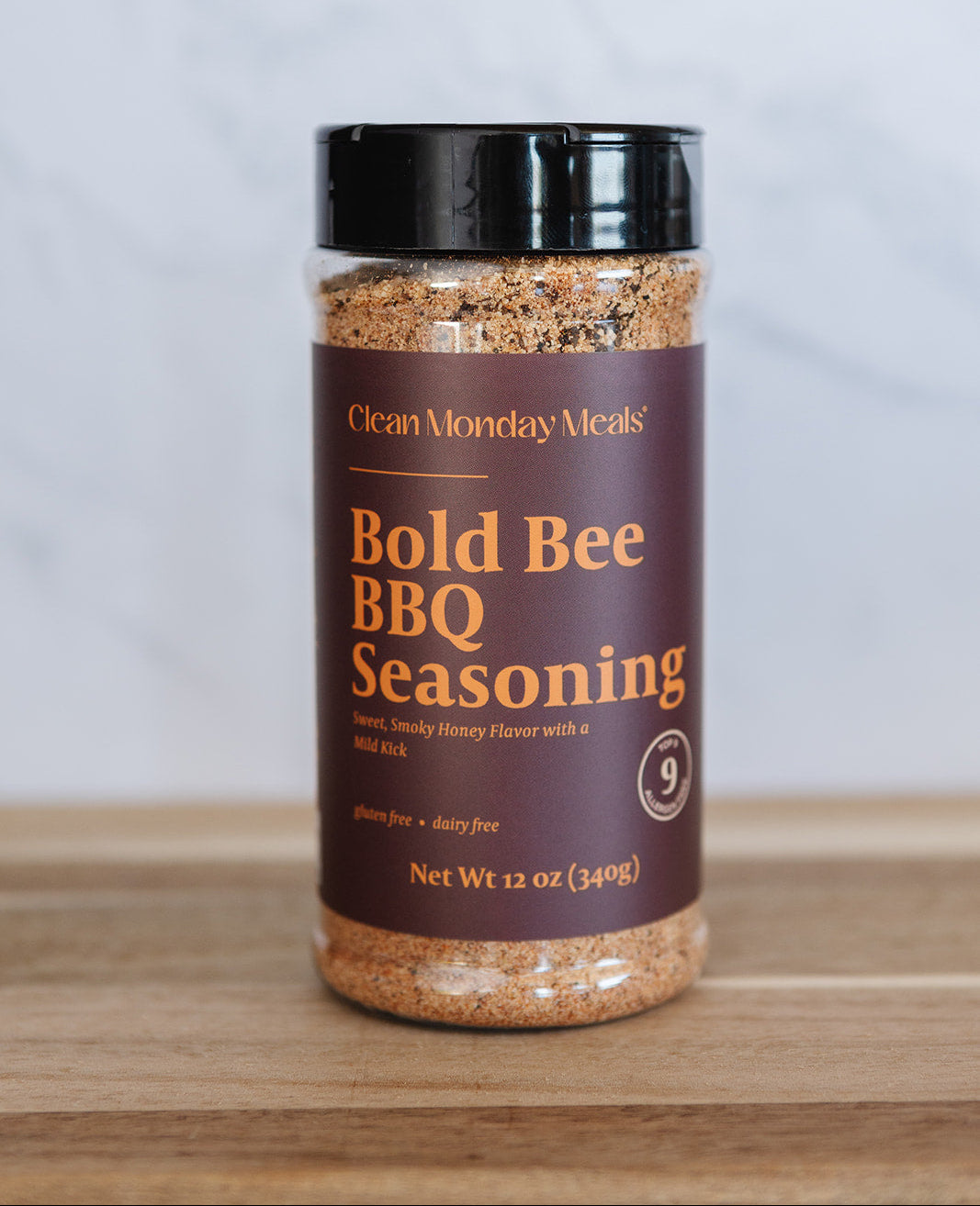 Bottle of Bold Bee BBQ Seasoning on a wooden surface with a white background