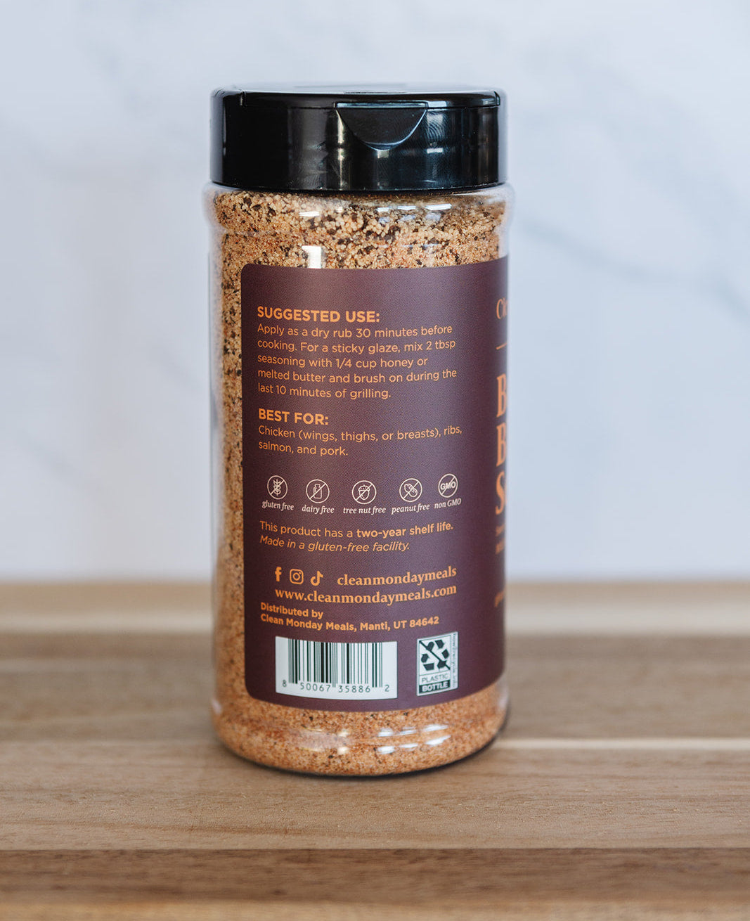 Spice jar with a black lid on a wooden surface and light gray background