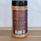 Spice jar with a black lid on a wooden surface and light gray background