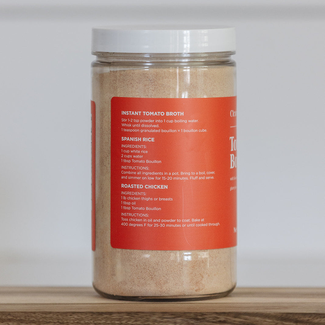 Jar of instant tomato broth on a wooden surface with a white background