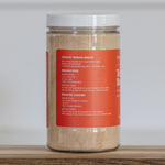 Jar of instant tomato broth on a wooden surface with a white background