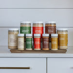 Collection of bouillon containers on a wooden board against a white kitchen cabinet background