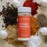 Bottle of Tomato Bouillon surrounded by spices on a textured surface
