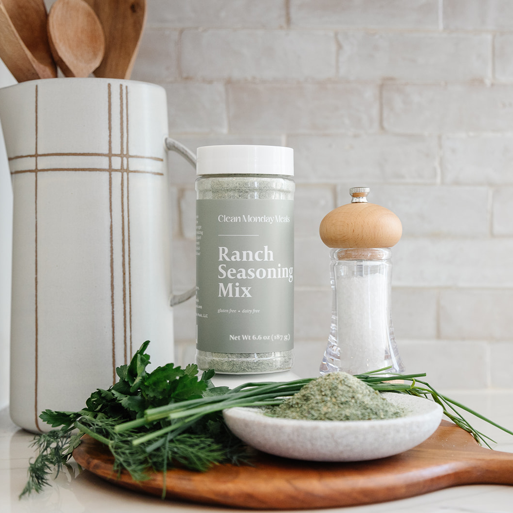 Clean Monday Meals Ranch Seasoning on a counter, next to some salt and herbs. Beautiful image. 