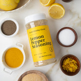 Lemon pepper seasoning container with lemons and spices on a marble surface