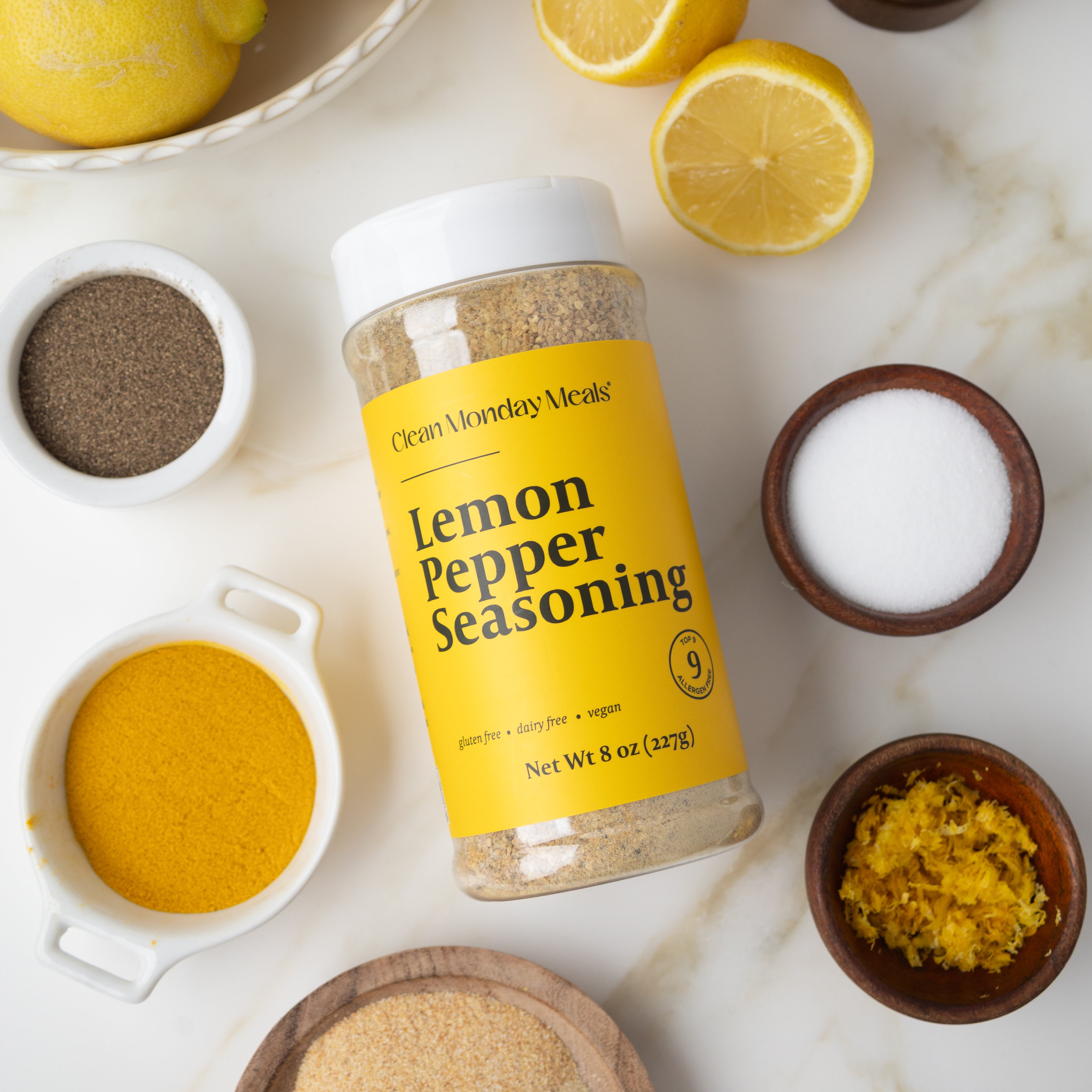 Lemon pepper seasoning container with lemons and spices on a marble surface