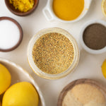 Close-up of a jar of ground spice with lemons and other spices on a light background