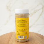 Jar of zesty lemon pepper butter on a wooden surface with a white background