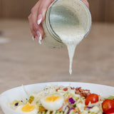 Pouring a mason jar of Clean Monday Meals Ranch Seasoning on a salad. 